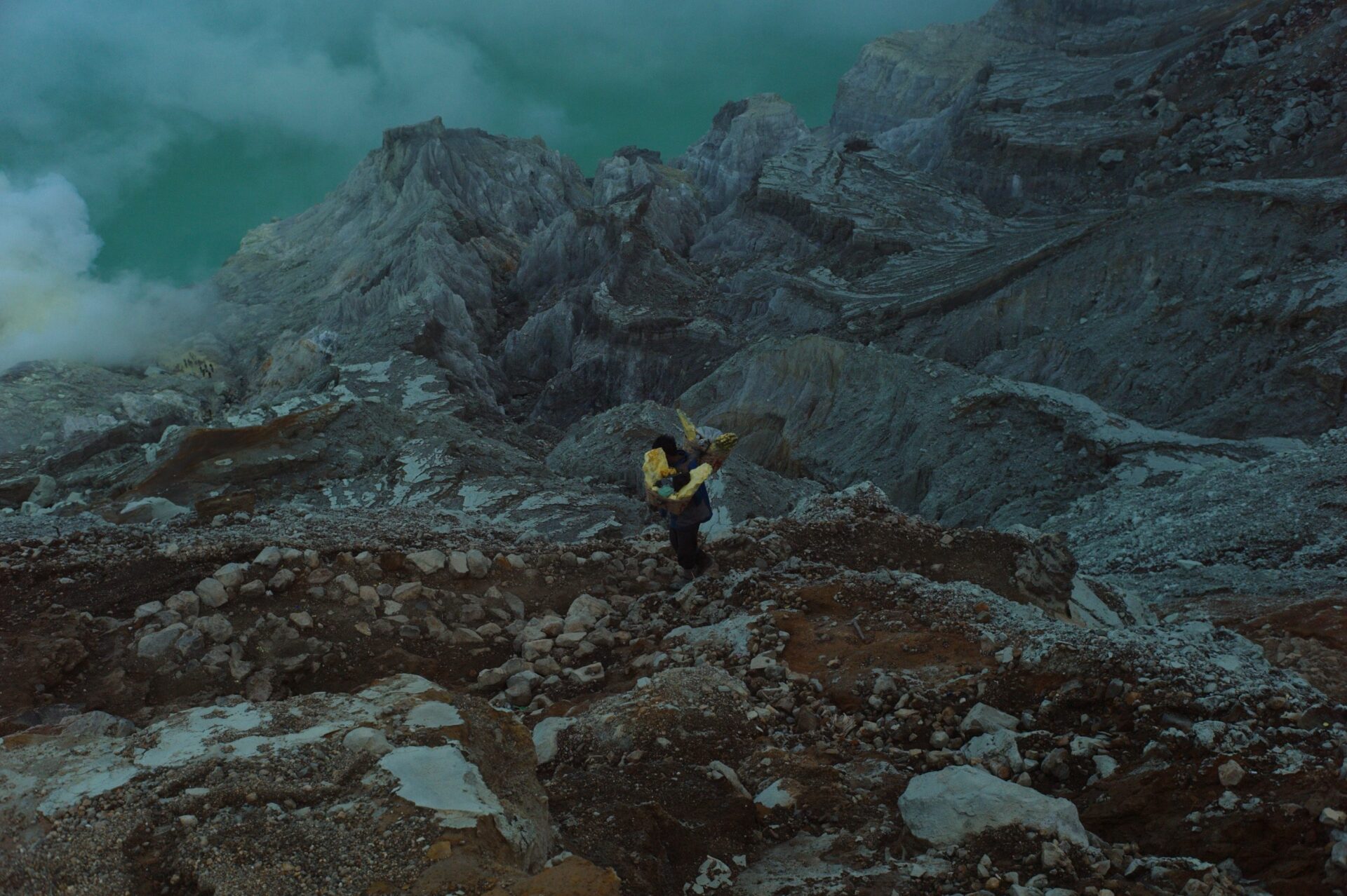A miner hikes out of the Kawah Ijen crater carrying a 70-100 kilo load of raw sulfur, 2011