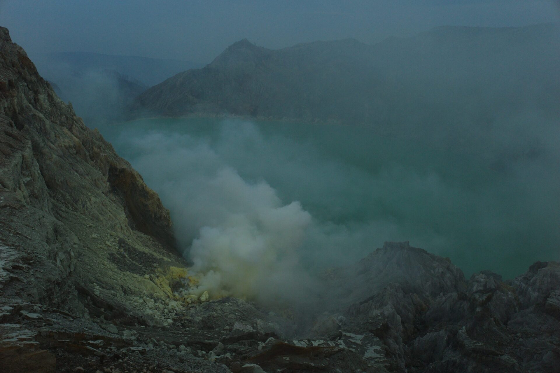 Sulfur deposits stain the sides of Ijen's crater with its acidic lake in the background