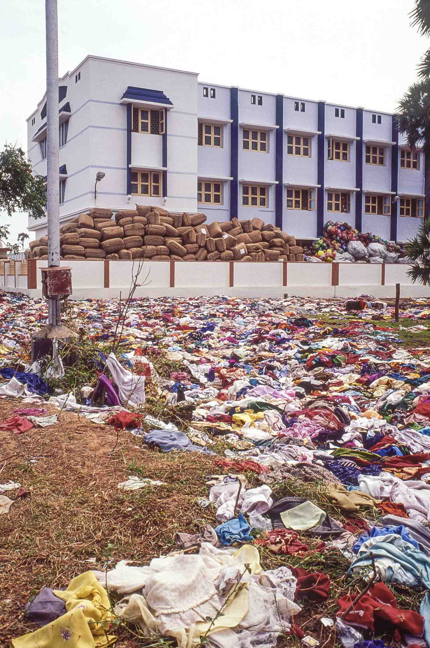 Donated clothes abandoned by tsunami survivors litters the ground outside of a relief warehouse. Nagapattinam, India, 2005